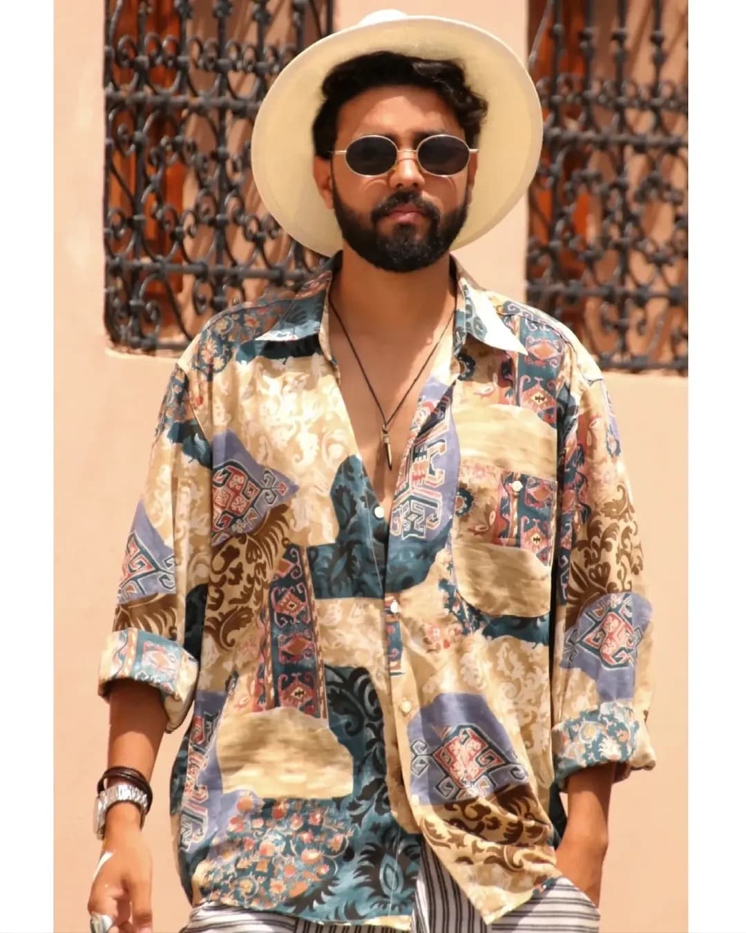 Kamal Hannouda wearing a patterned shirt and sun hat, standing in front of an ornate ironwork window in Marrakech.