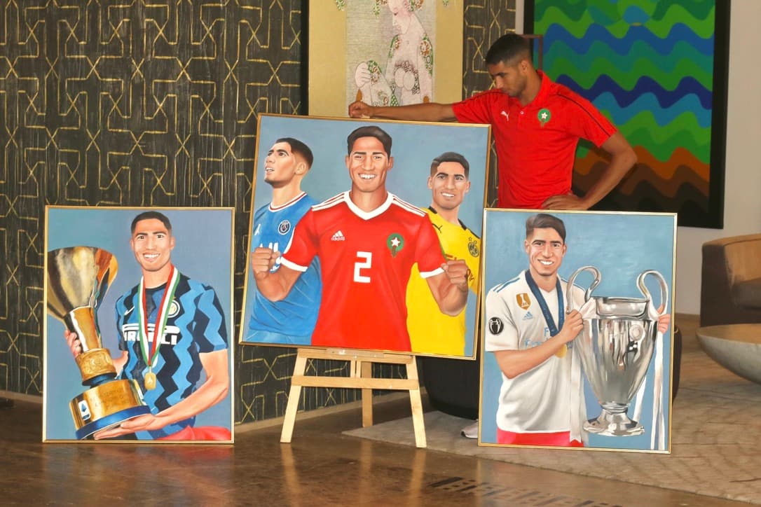 Three framed footballer portrait paintings of Achraf Hakimi displayed together, with him standing behind them.