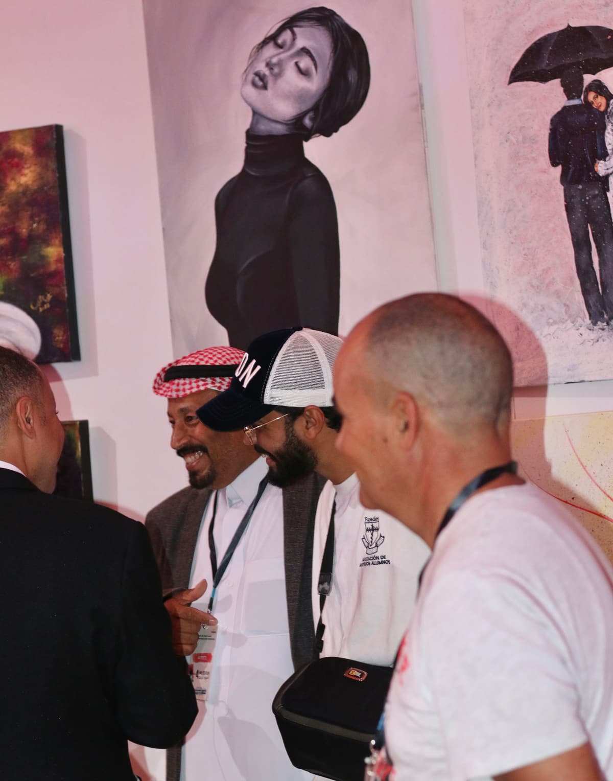 A crowd of visitors viewing paintings, including a portrait of a woman in a turtleneck, at a gallery exhibition.