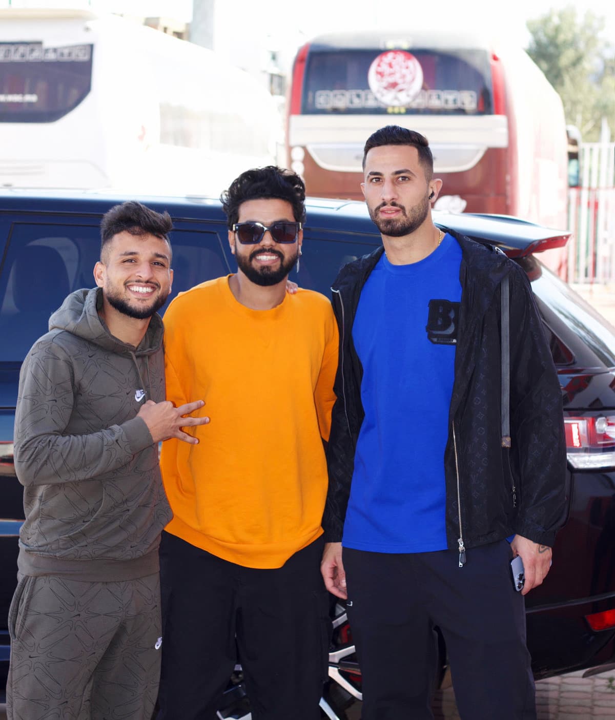Kamal Hannouda with Aymane El Hassouni and a friend posing outdoors near a team bus.
