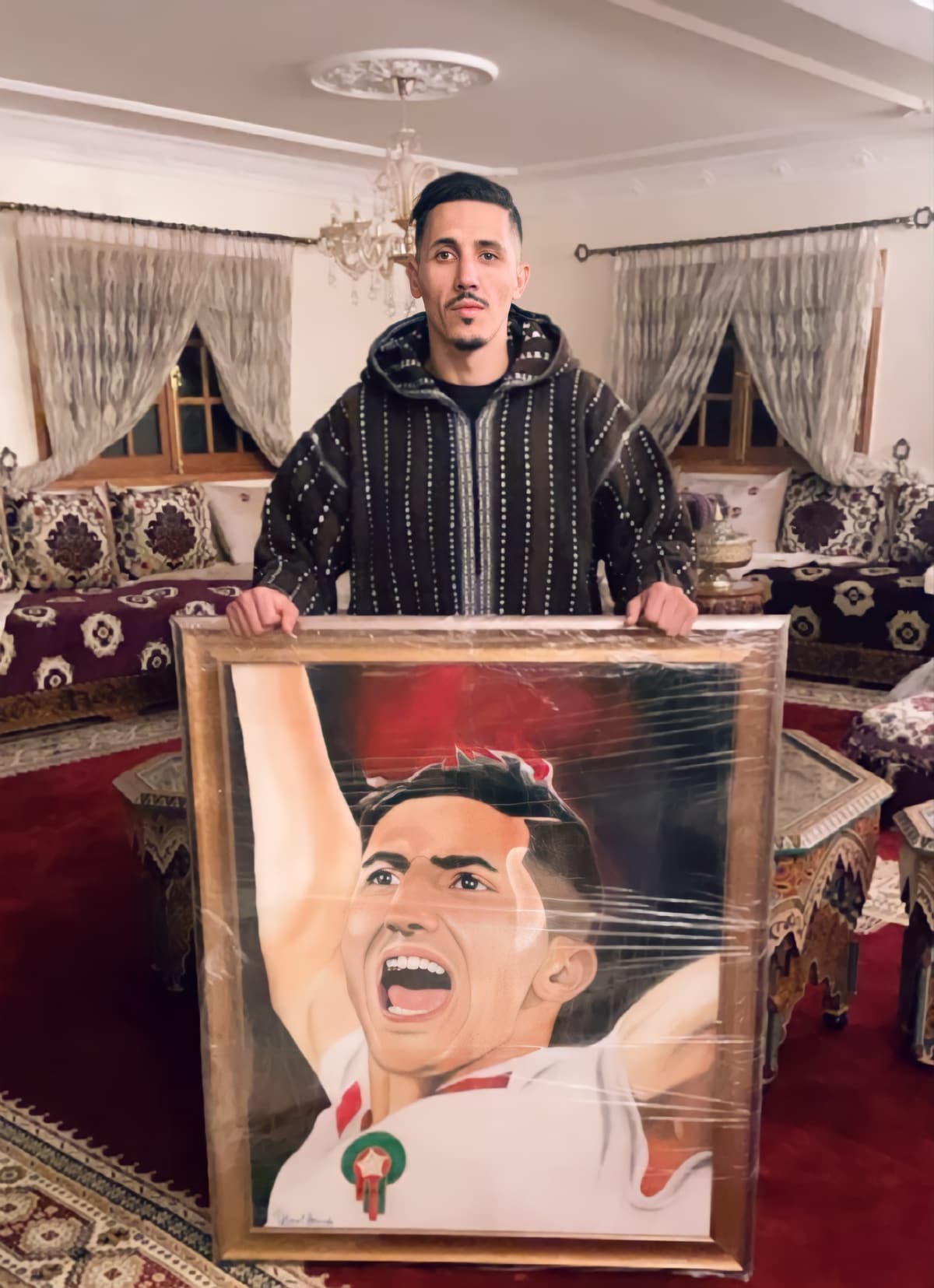 Fayçal Fajr holding his shrink-wrapped framed portrait painting in a traditional Moroccan salon.