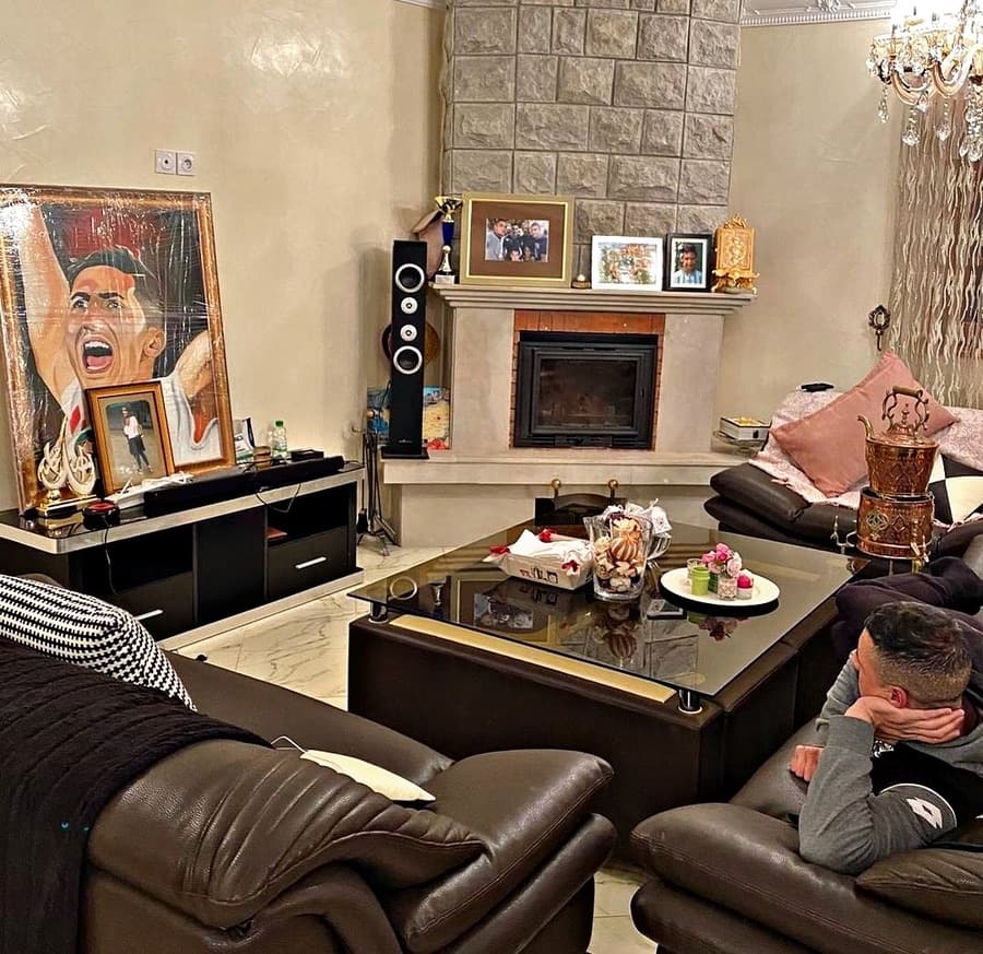 The framed portrait painting of Fayçal Fajr displayed on a sofa in a living room.