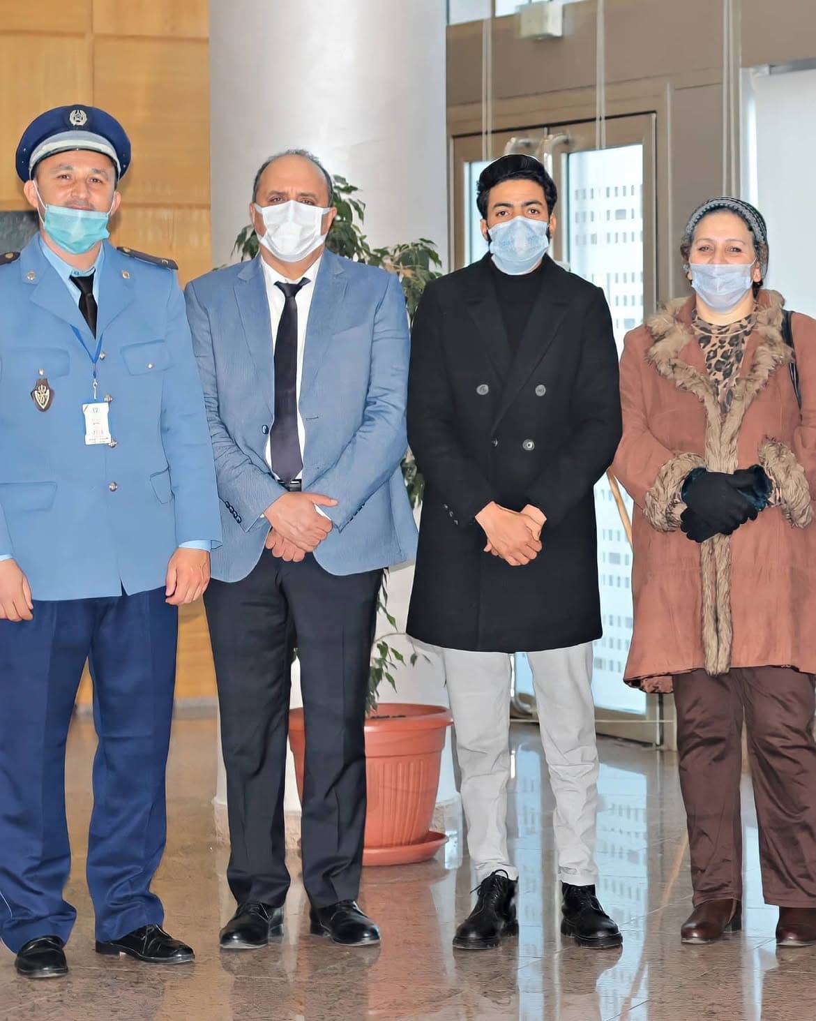 Kamal Hannouda posing with three Moroccan Customs officials in a building lobby, all wearing face masks.